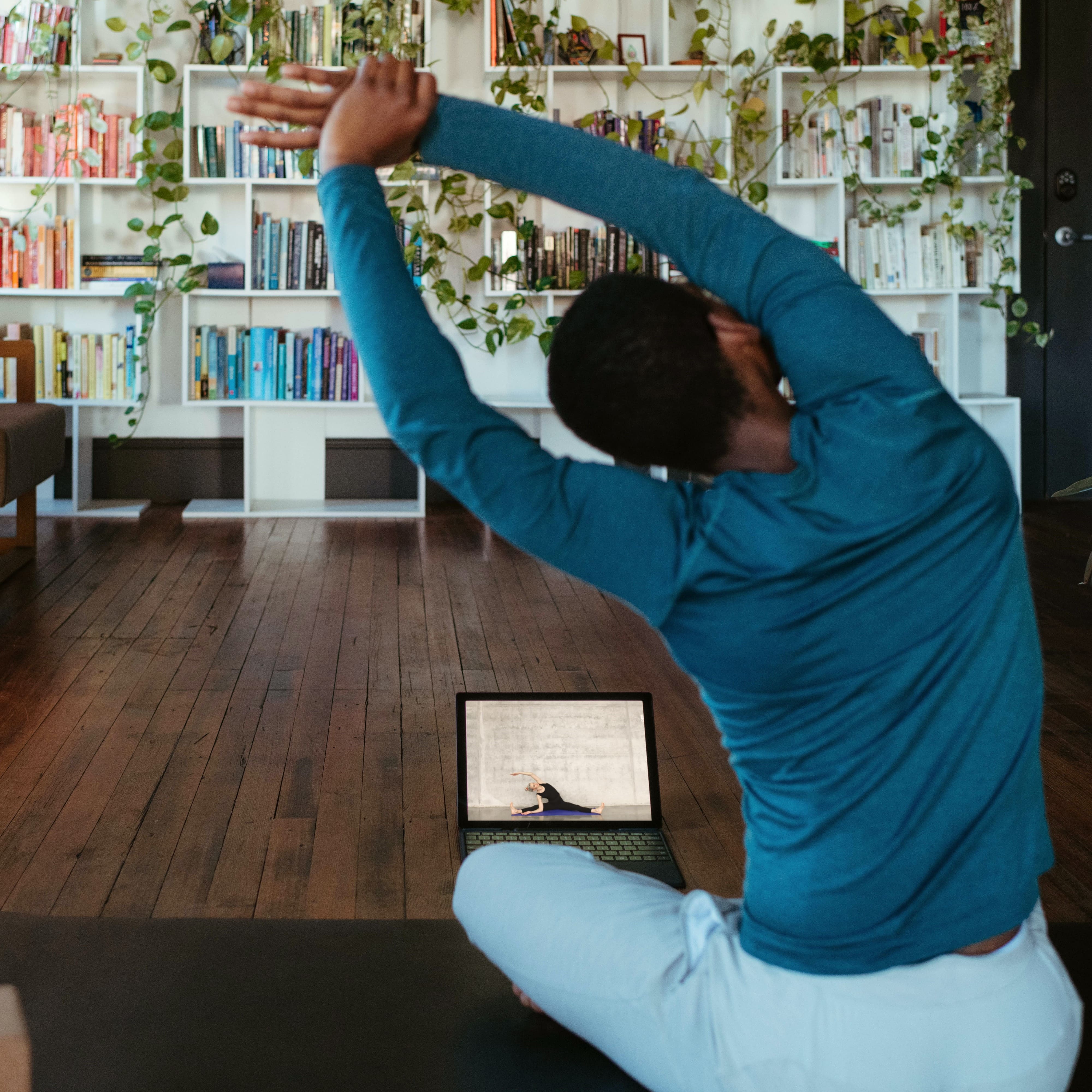 Man doing yoga at home with personal trainer via video call